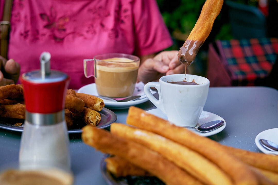 People enjoying churros with hot chocolate in Madrid, Spain.