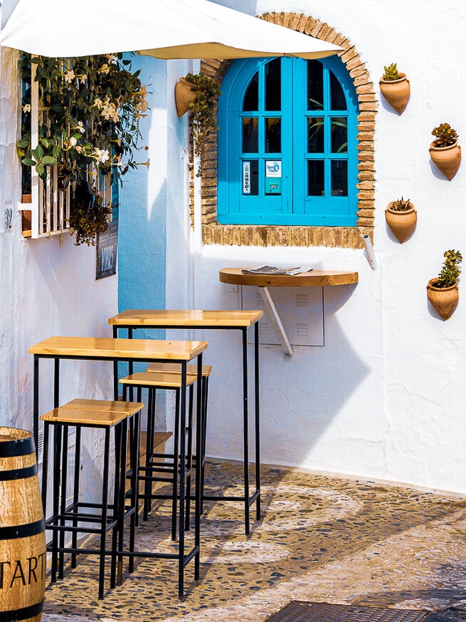Cozy corner bar at a white washed house with blue windows in Frigiliana, Andalusia, Spain.